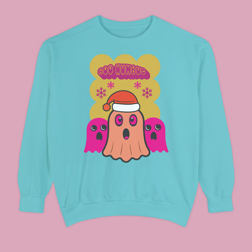 A holiday sweatshirt featuring a cute ghost character wearing a Santa hat, with two smaller ghosts on either side. Above them is the playful text "Boo Humbug," surrounded by snowflakes and festive elements. The design humorously combines spooky and festive themes for a unique holiday look.